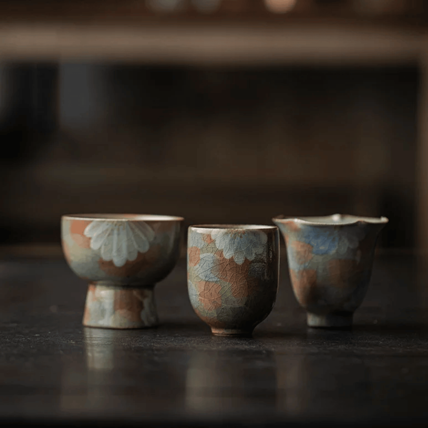 Three ceramic cups with floral patterns on a dark surface