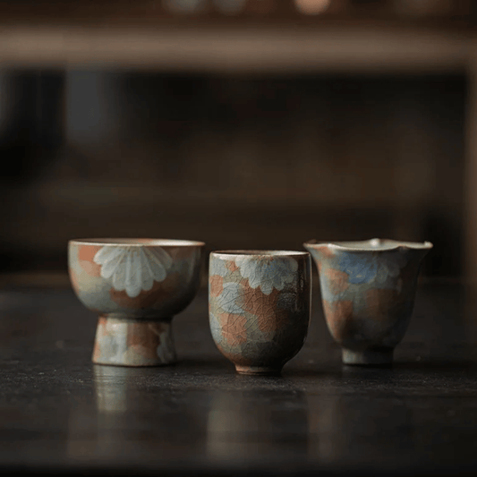 Three ceramic cups with floral patterns on a dark surface