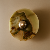 Decorative wall light fixture with a marbled design on a beige background