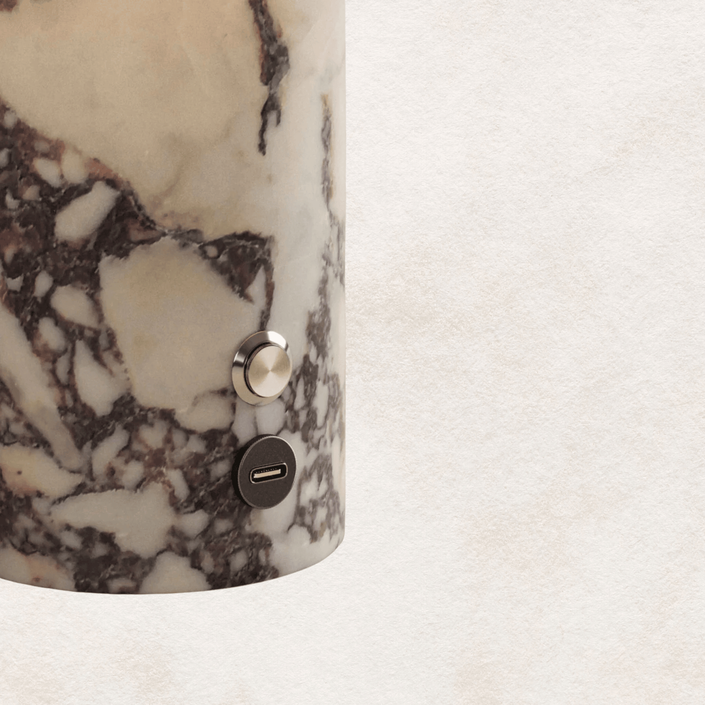 Marble-patterned cylindrical object with a metallic button on a light background