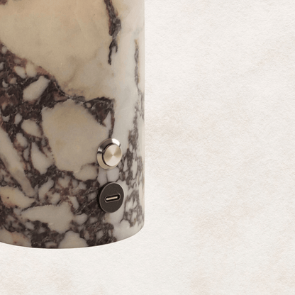 Marble-patterned cylindrical object with a metallic button on a light background