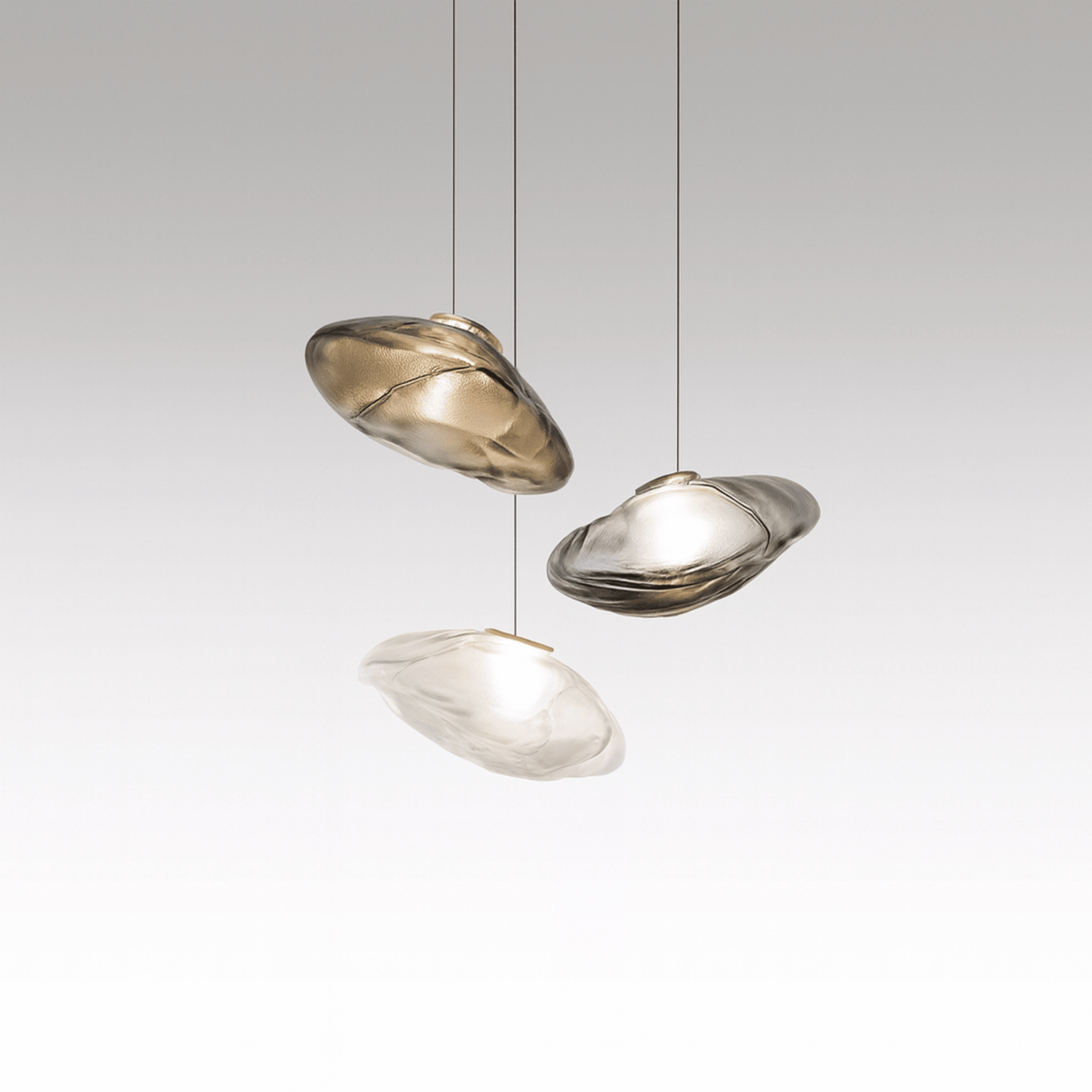 Three modern pendant lights hanging against a gray background