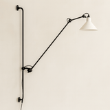 Wall-mounted lamp with a long arm and white shade on a beige wall