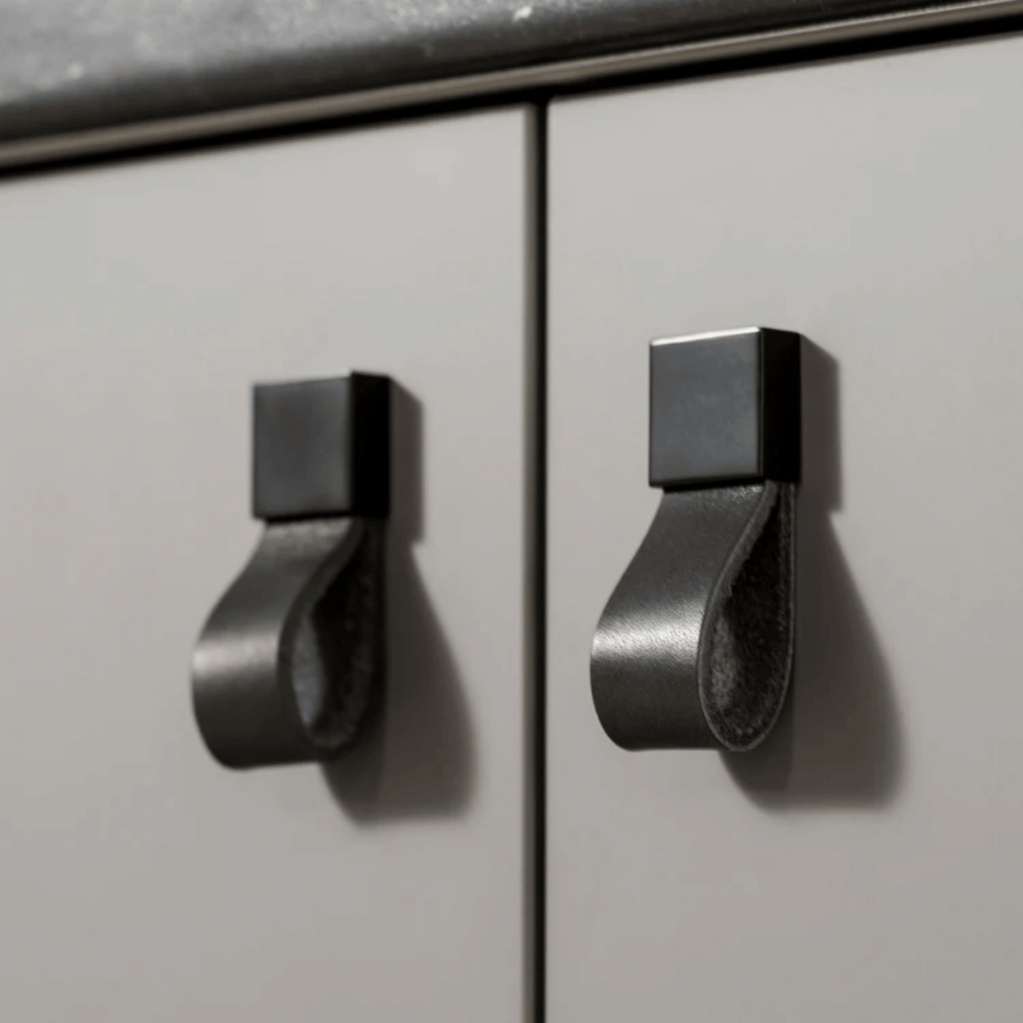 Metallic cabinet handles on a light gray cabinet door
