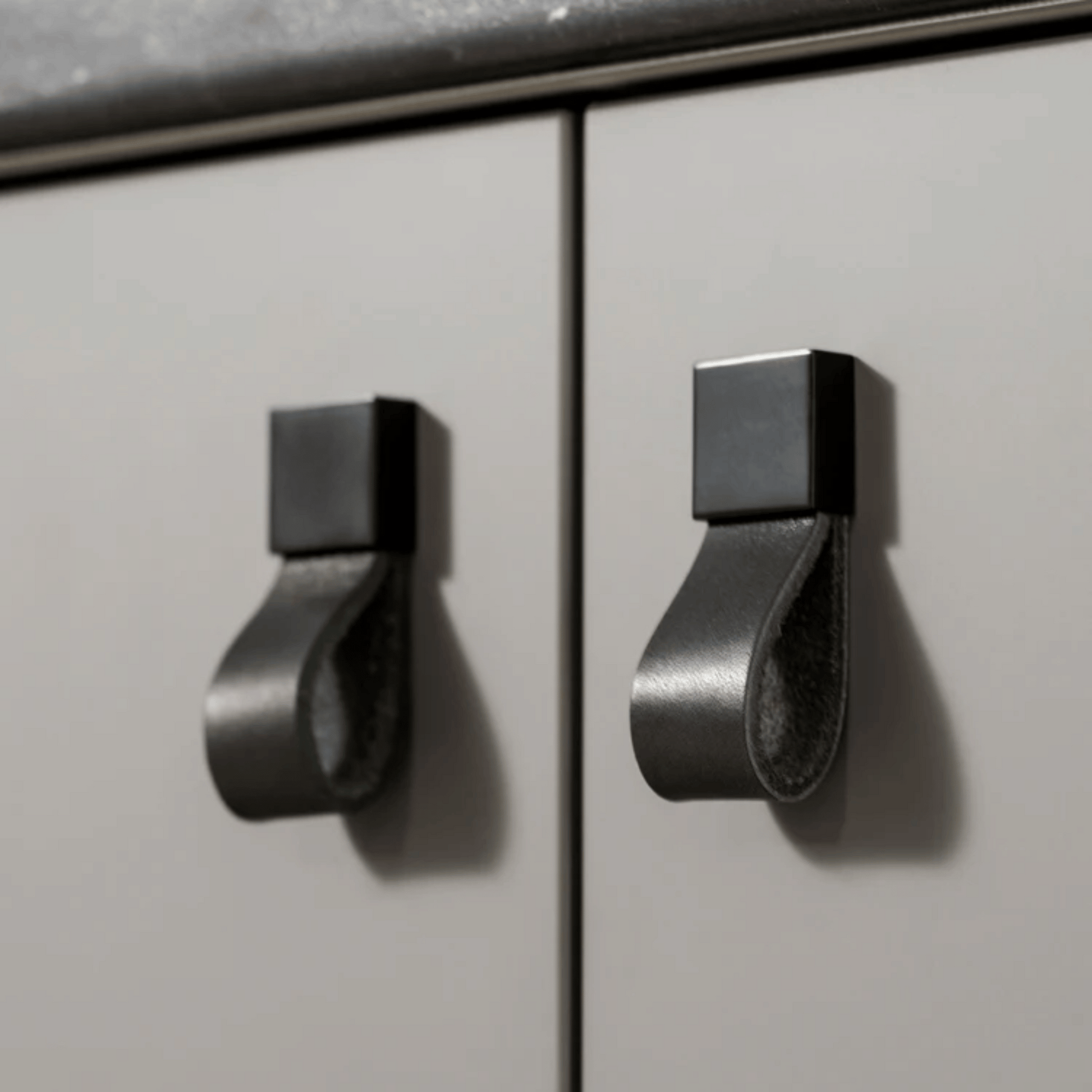 Metallic cabinet handles on a light gray cabinet door