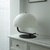 White table lamp on a white dresser with blinds in the background