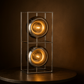 Decorative lamp with two illuminated bulbs in a metal cage on a dark surface.
