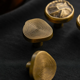 Gold cabinet knobs with intricate designs on a black surface