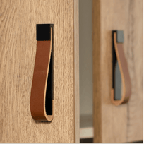 Close-up of wooden furniture with leather handles on a light wood background