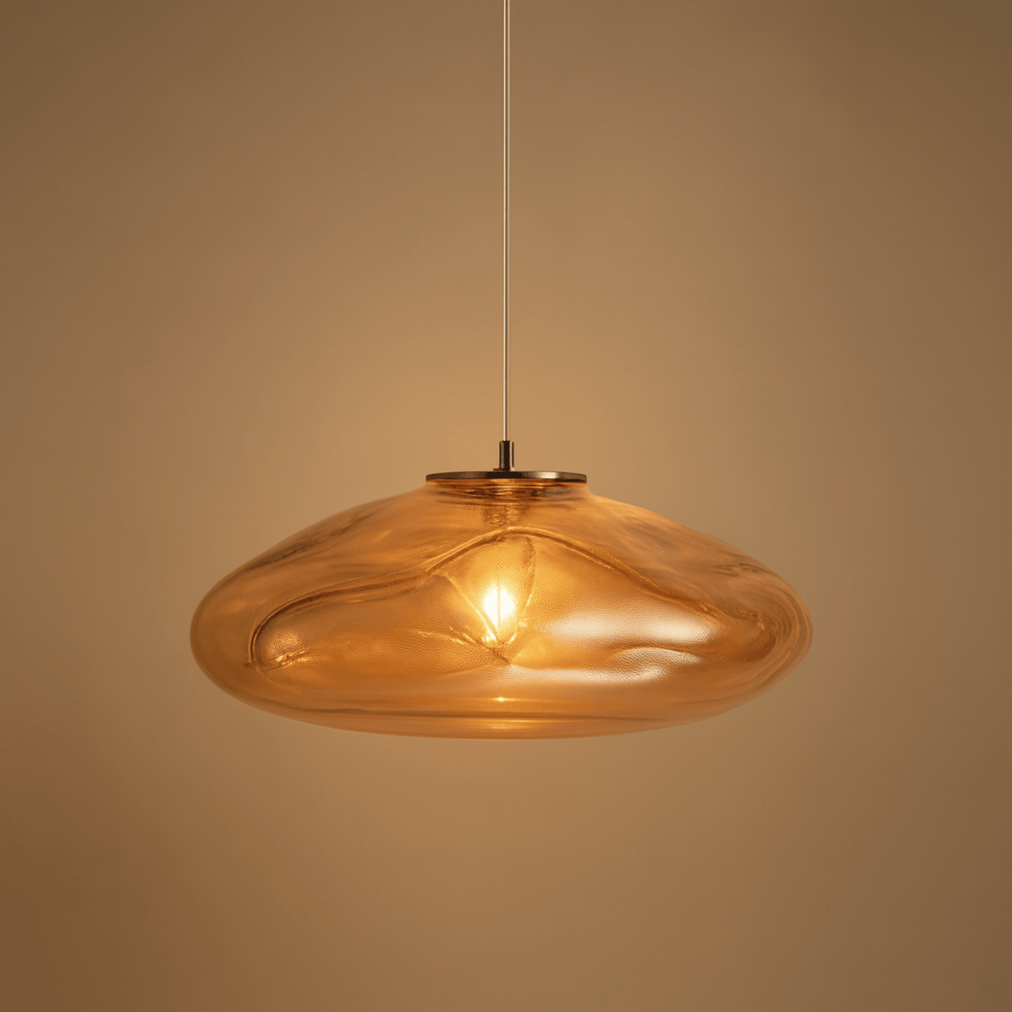Amber glass pendant light against a beige background