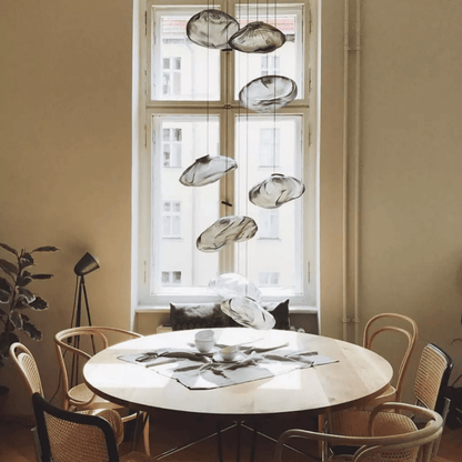 Round dining table with chairs in a room with large windows and modern pendant lights.