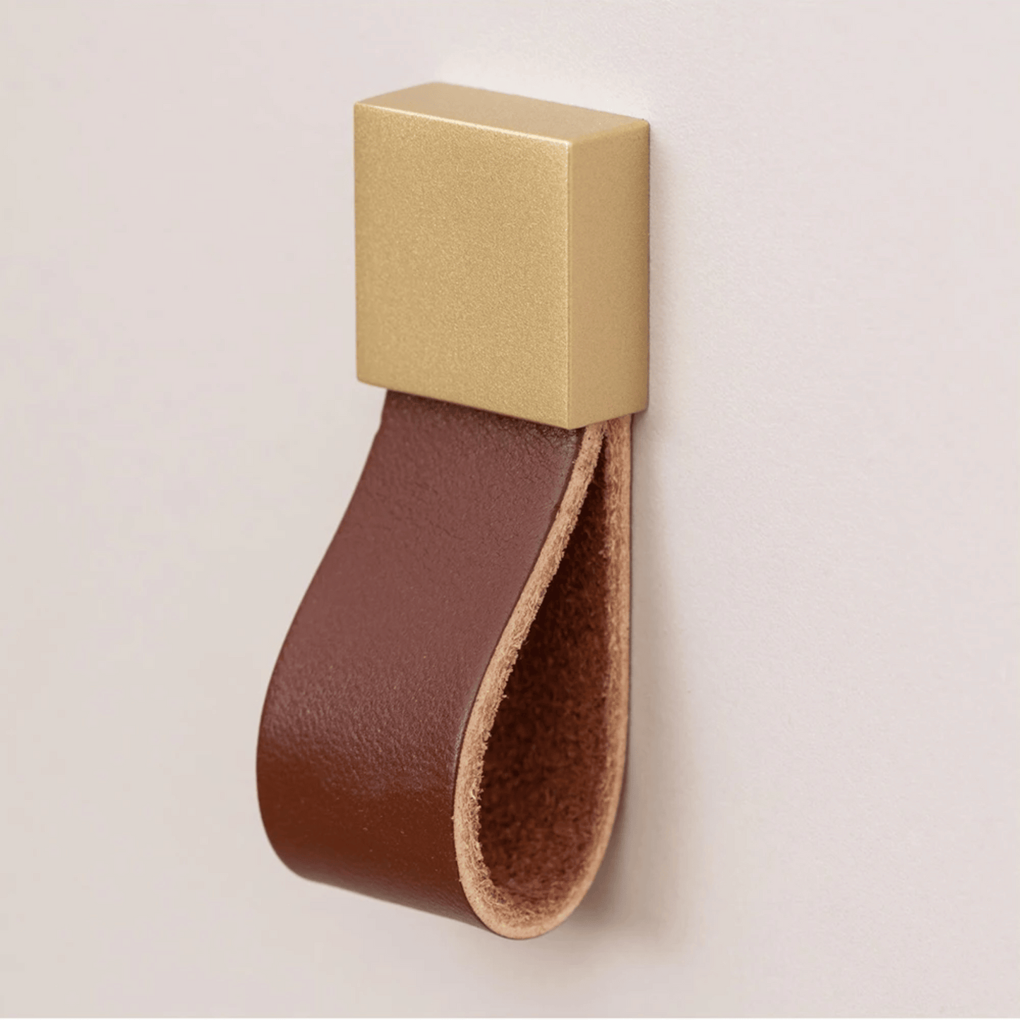 Gold square with a brown leather strap on a beige background