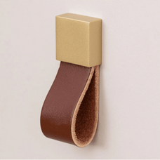 Gold square with a brown leather strap on a beige background