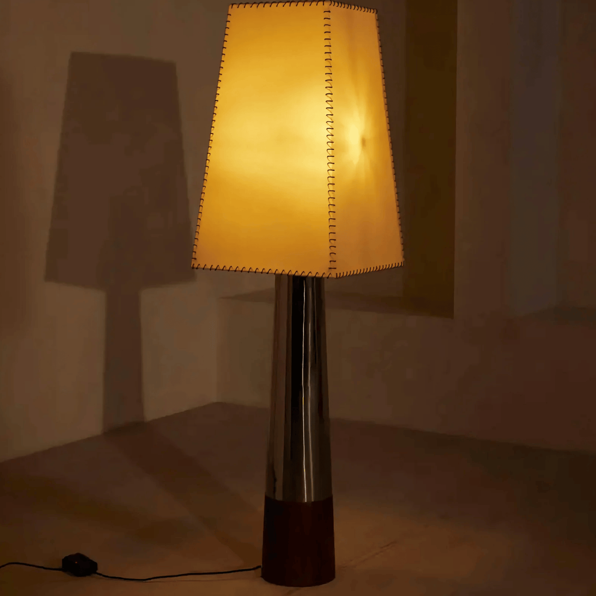 Floor lamp with a textured shade casting a shadow on a wall