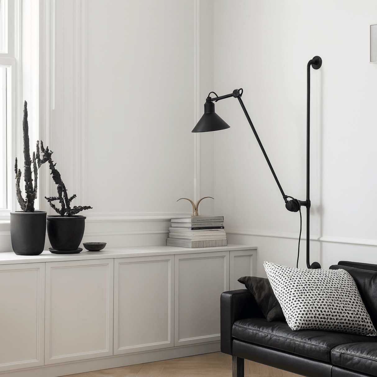Modern living room with a black floor lamp, black sofa, and decorative plants.
