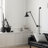 Modern living room with a black floor lamp, black sofa, and decorative plants.