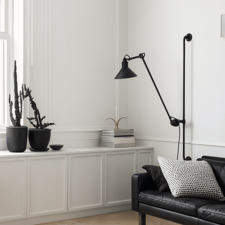 Modern living room with a black floor lamp, black sofa, and decorative plants.