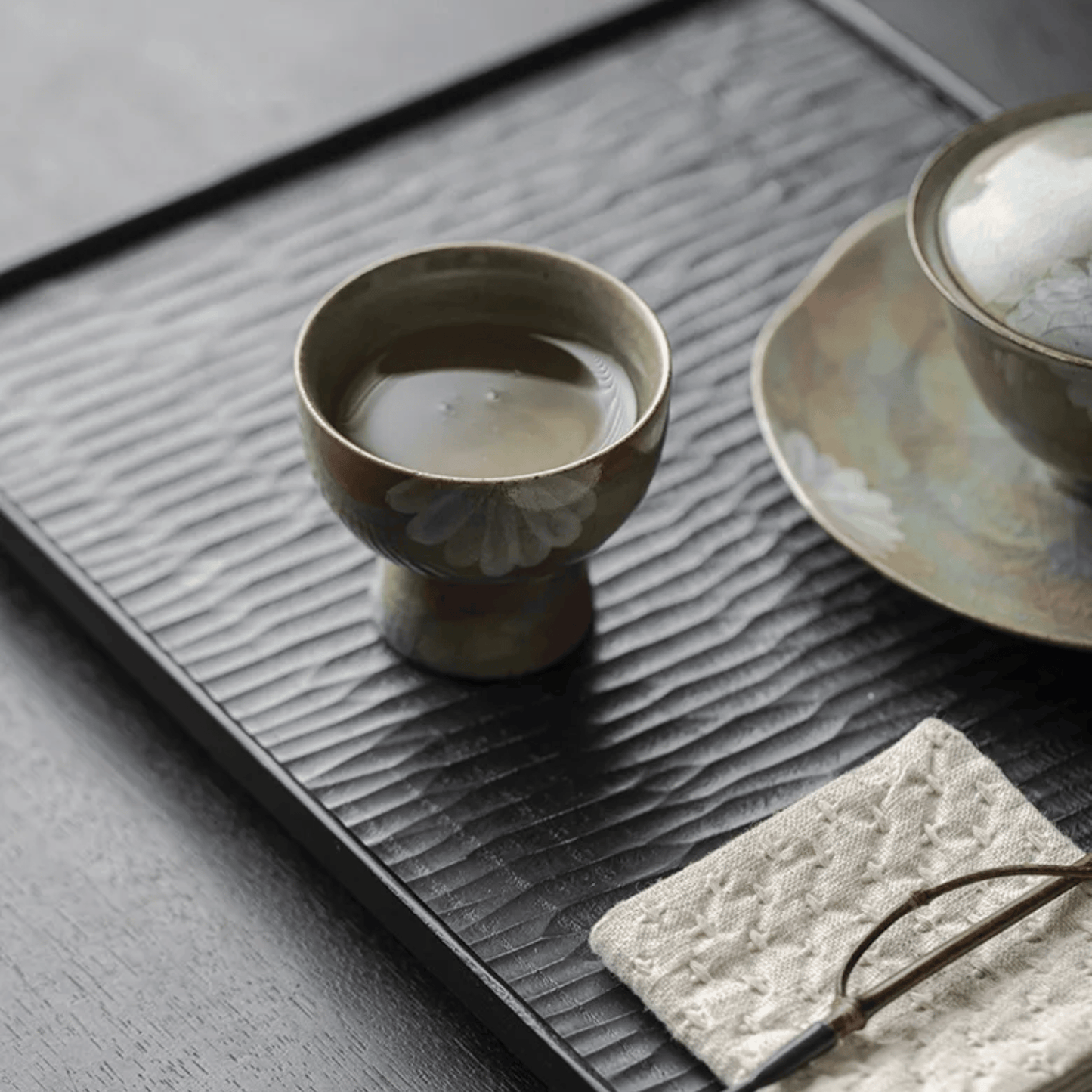 Ceramic cup with a floral design on a textured black tray.