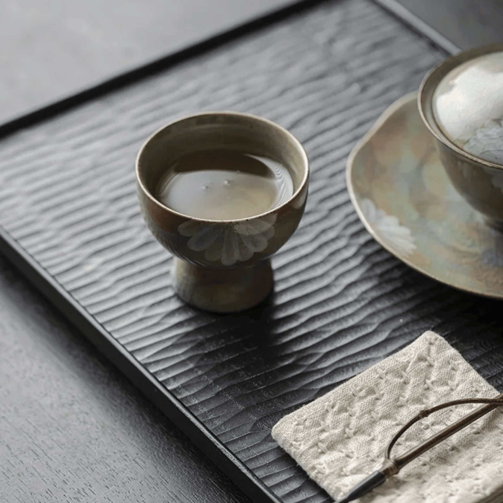 Ceramic cup with a floral design on a textured black tray.