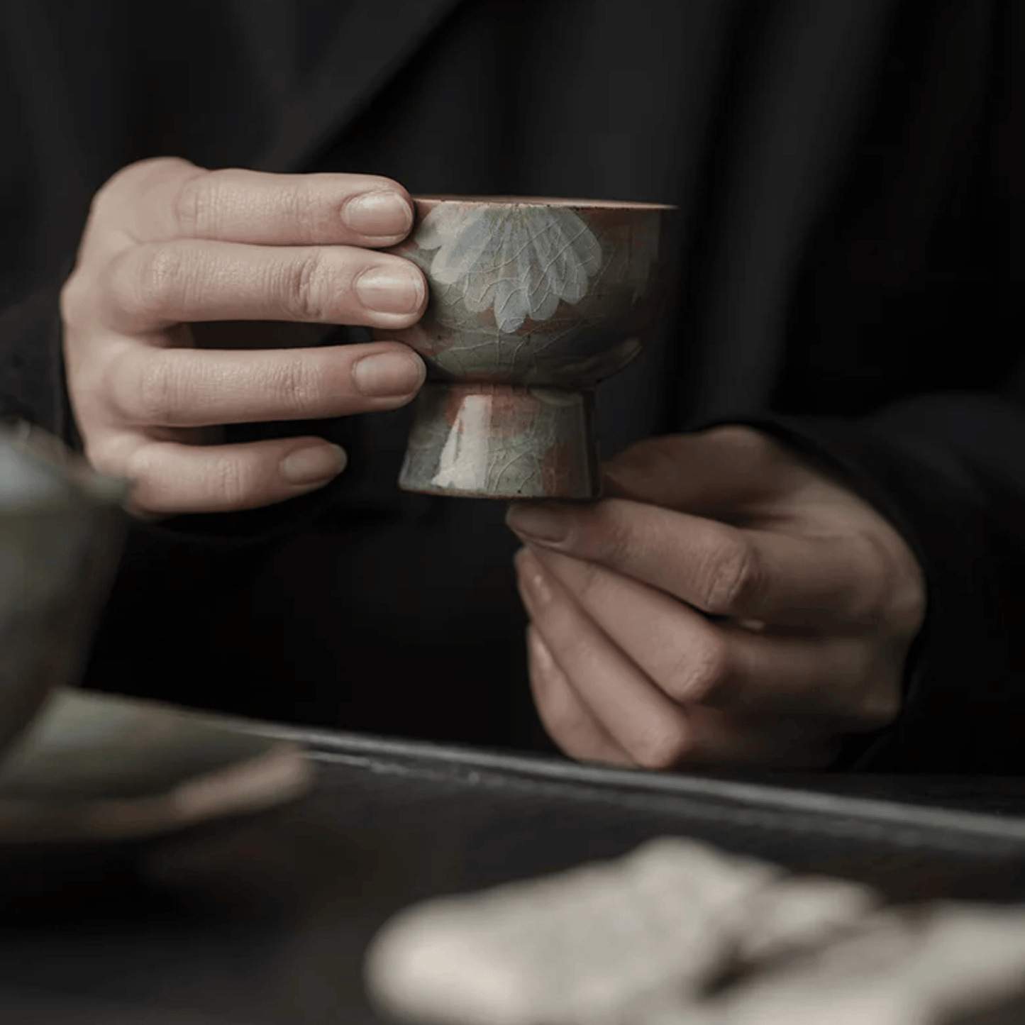 Person holding a traditional ceramic cup with intricate designs.