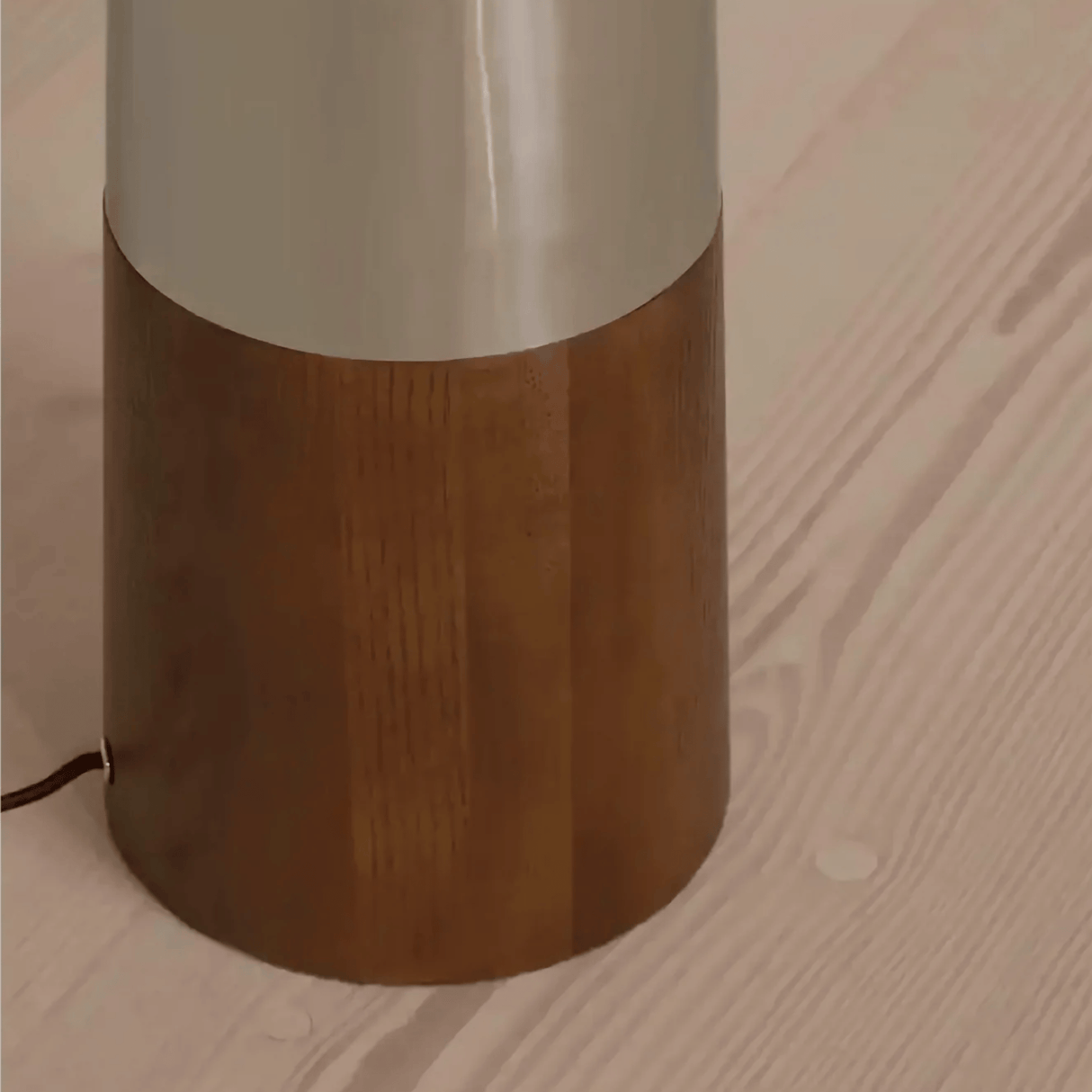 Floor lamp with wooden base and white shade on a wooden floor