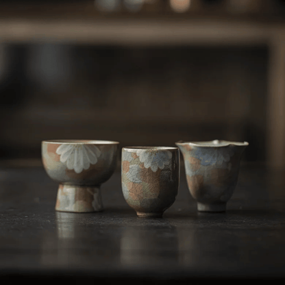 Three ceramic cups with floral patterns on a dark surface