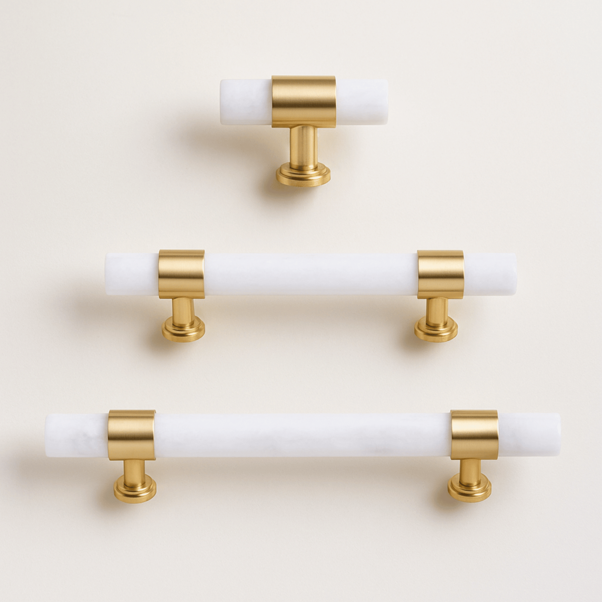 Set of gold and white cabinet handles on a beige background