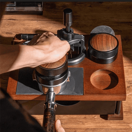 Hand using a manual coffee grinder on a wooden surface
