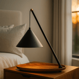 Black lamp with wooden base on a nightstand in a bedroom setting