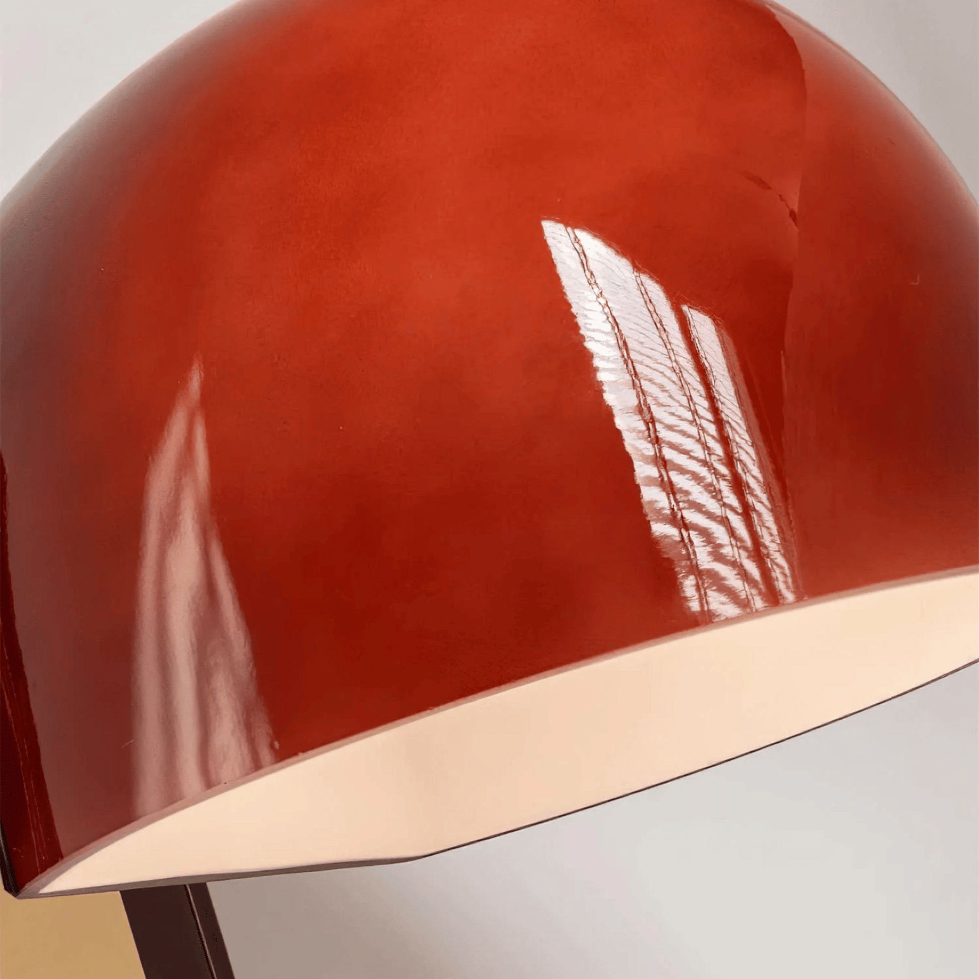 Close-up of a red lampshade with a metallic edge on a neutral background
