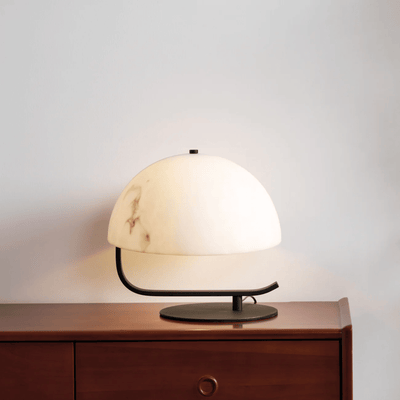 Table lamp with a white shade and black base on a wooden surface against a light gray background