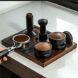 Coffee grinder and various coffee grounds on a wooden tray with a white marble background