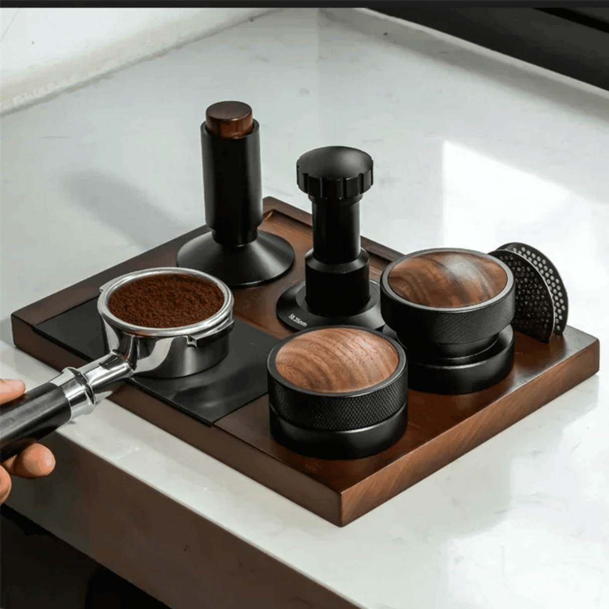 Coffee grinder and various coffee grounds on a wooden tray with a white marble background