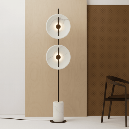 Modern floor lamp with two circular glass shades in a minimalistic room.
