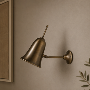 Bronze wall lamp on a beige wall with a plant in the corner