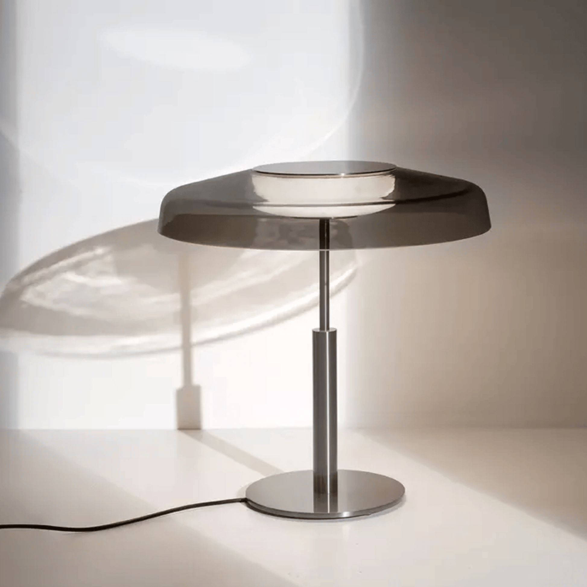 Modern table lamp with a metallic base and glass shade on a white surface.