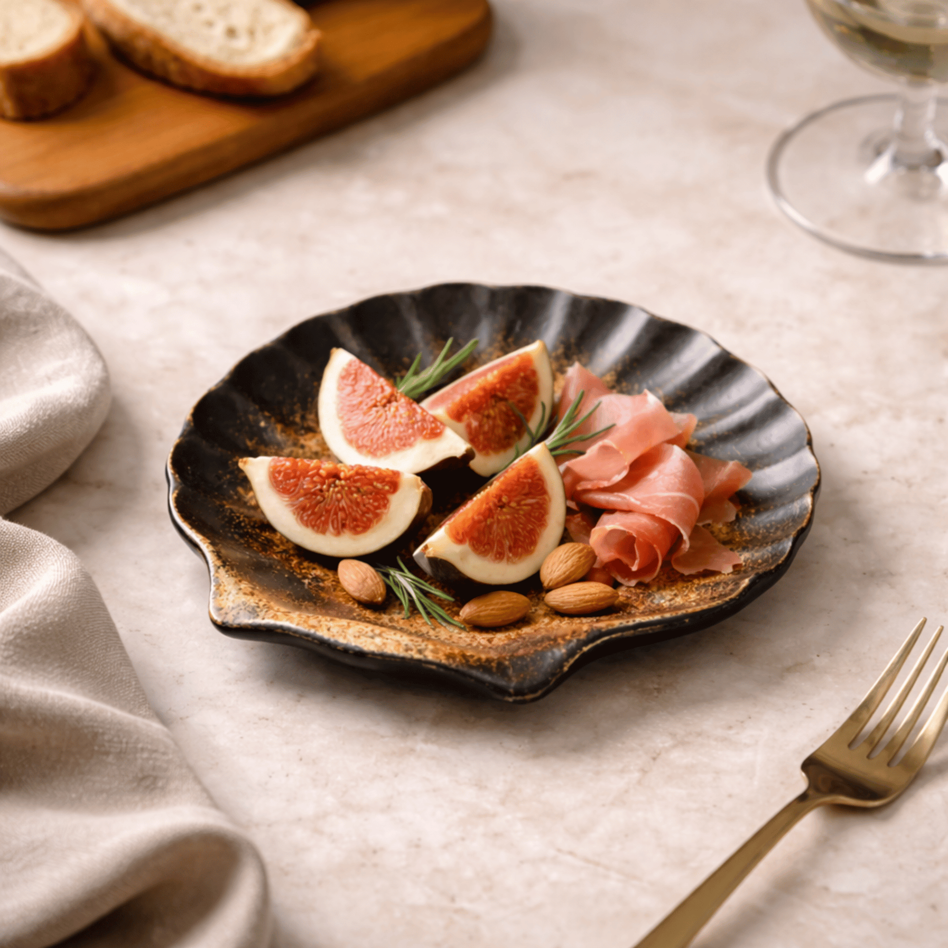 Plated appetizer with figs, prosciutto, and almonds on a textured plate with a fork beside it.