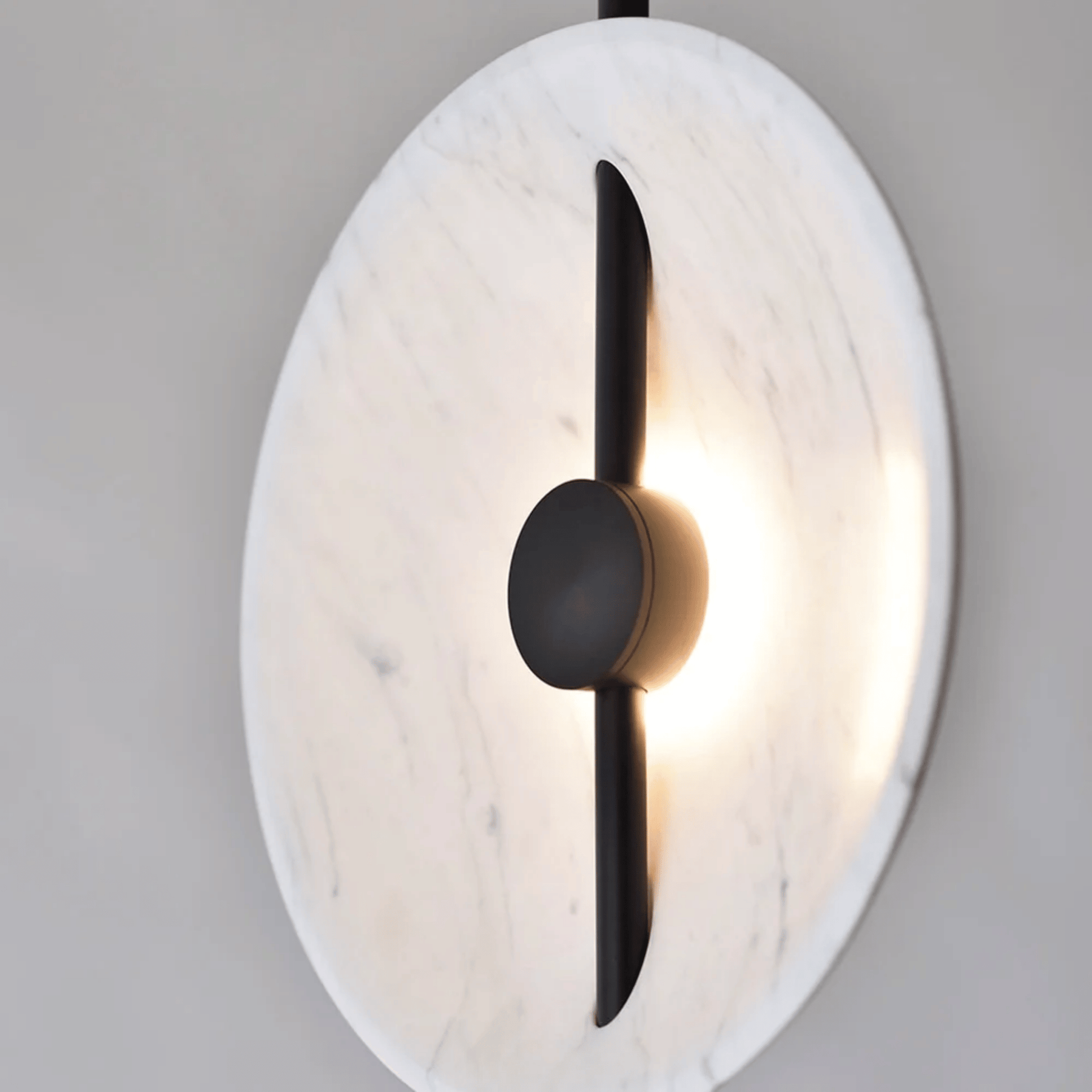 Modern wall sconce with marble-like finish and black accent on a gray background