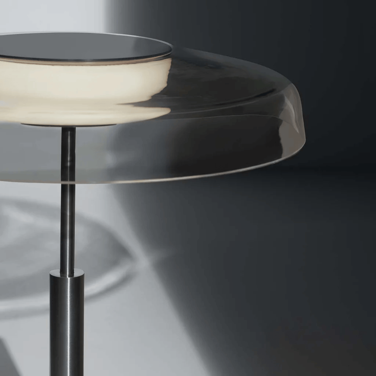 Modern side table with glass top and metal base on a dark background