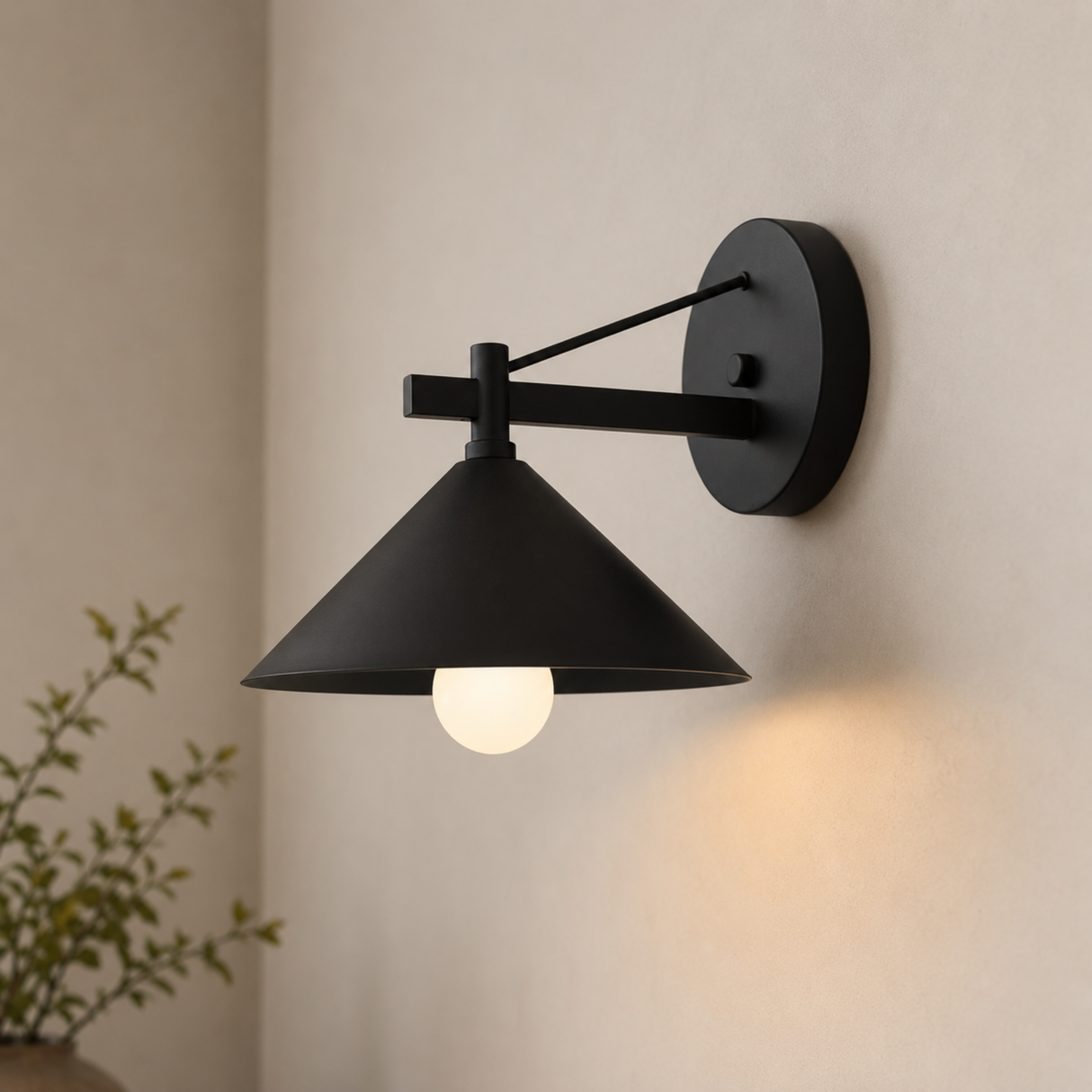 Black wall-mounted lamp on a beige wall with a plant in the corner.