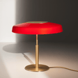 Red table lamp with gold base on a neutral background