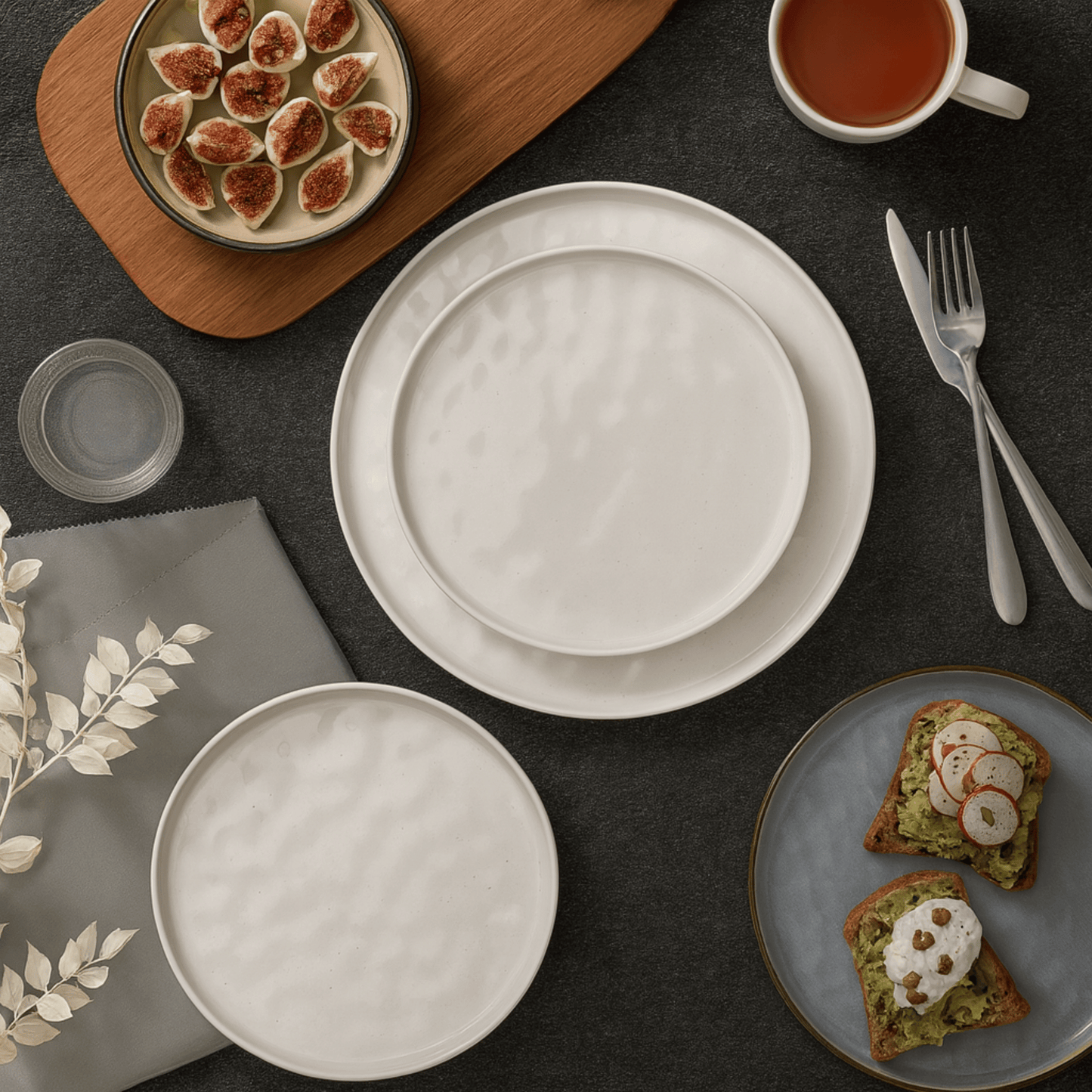 Table setting with white plates, a cup of tea, and a plate of toast with avocado spread.