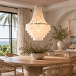 Dining room with a large chandelier, round wooden table, and wicker chairs.