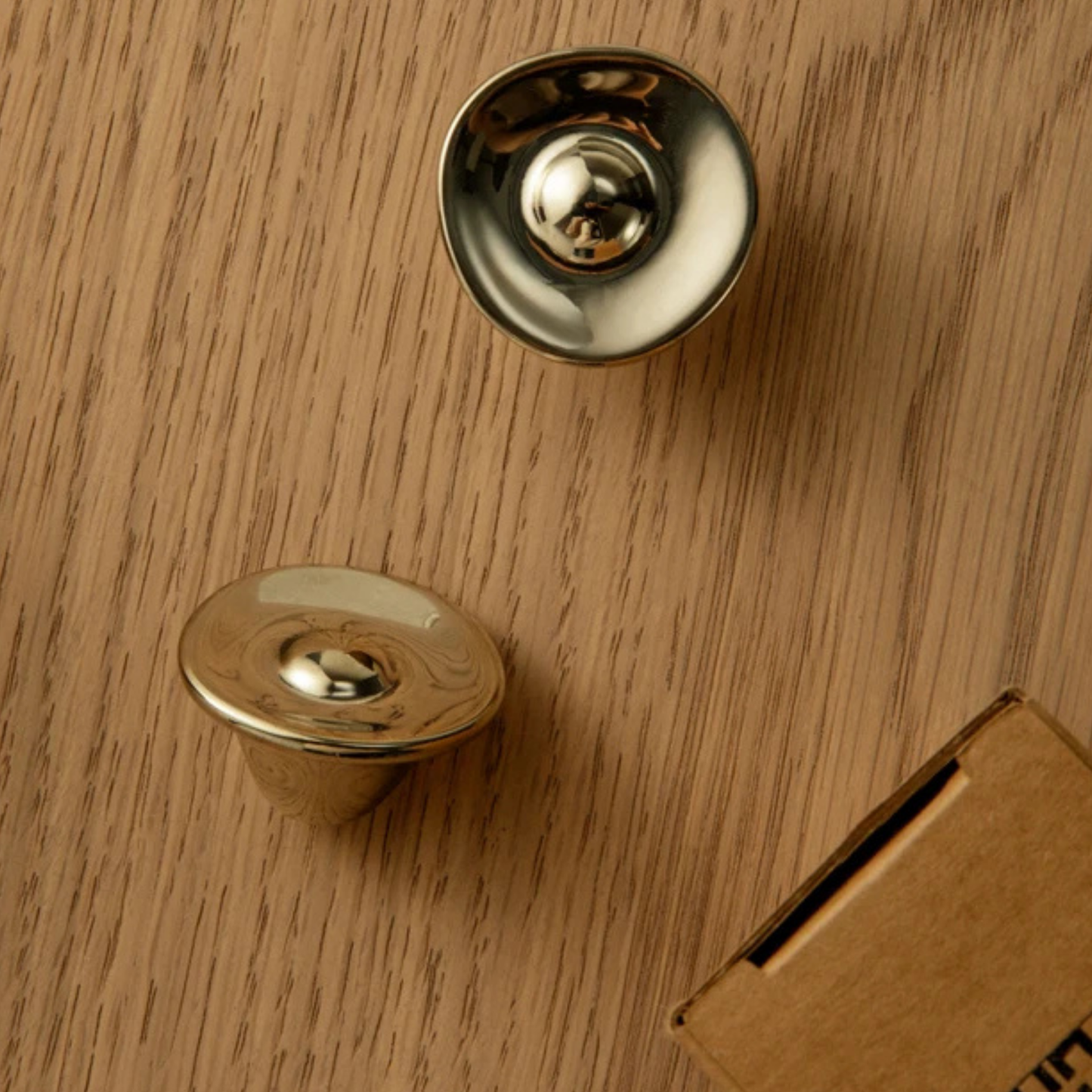 Metallic dome-shaped cabinet knobs displayed on a wooden surface