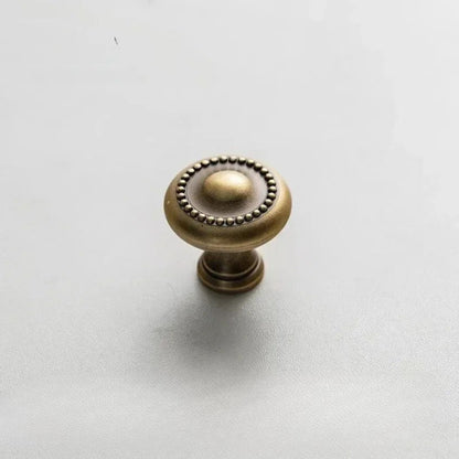 A pair of golden drawer knobs placed on a marble countertop with soft lighting.