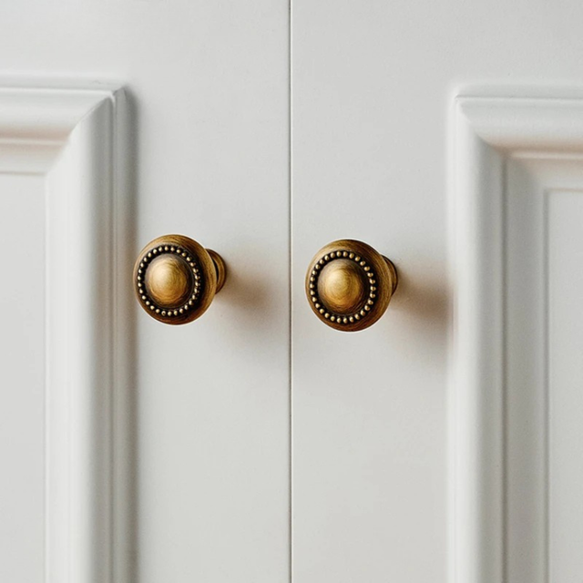 Do golden vintage-style round cabinet knobs lagaye hue white cupboard doors pe.