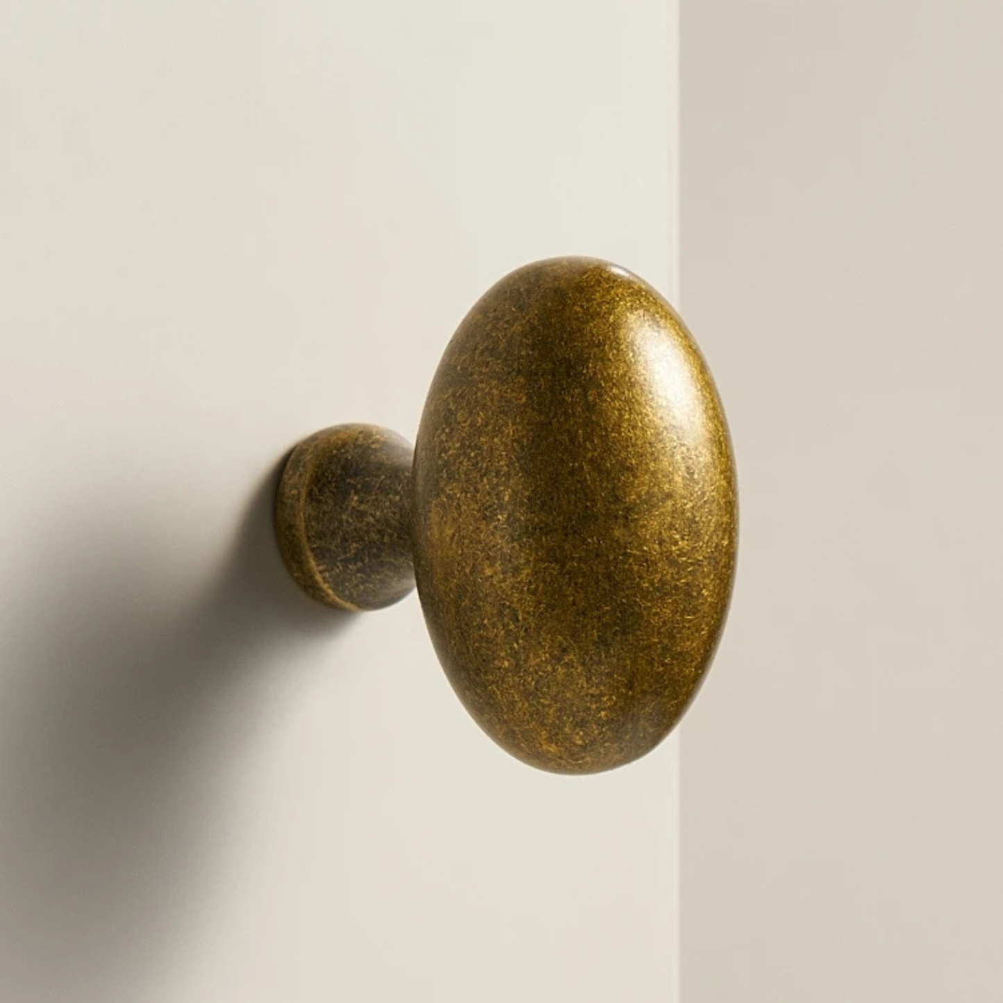 A vintage-style oval brass door knob mounted on a white door, showing a smooth metallic texture.