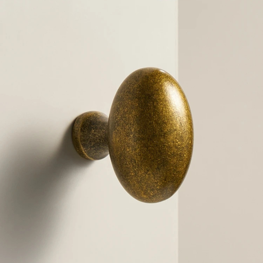 A vintage-style oval brass door knob mounted on a white door, showing a smooth metallic texture.