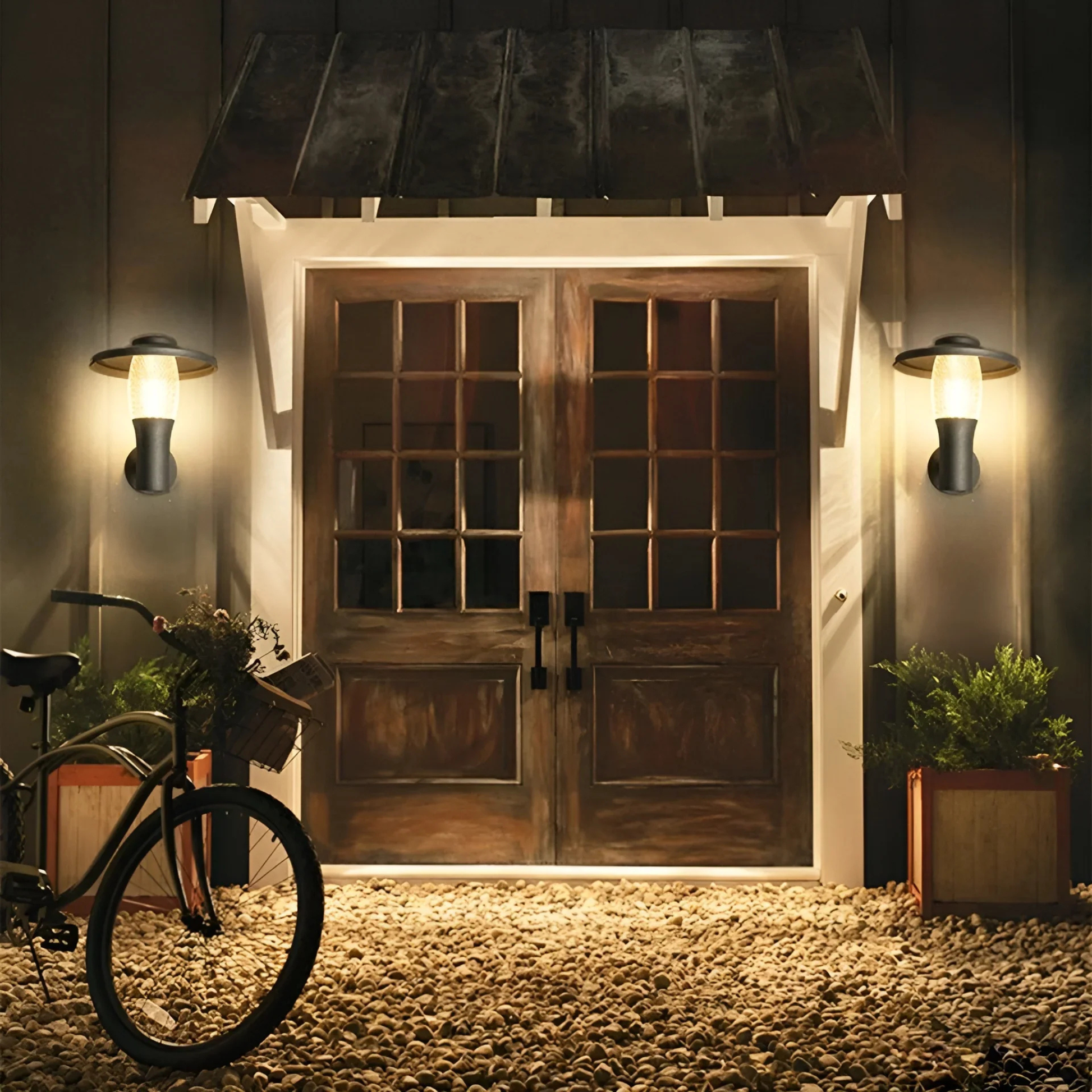 Modern house entrance with warm outdoor wall lights illuminating a wooden double door and bicycle nearby
