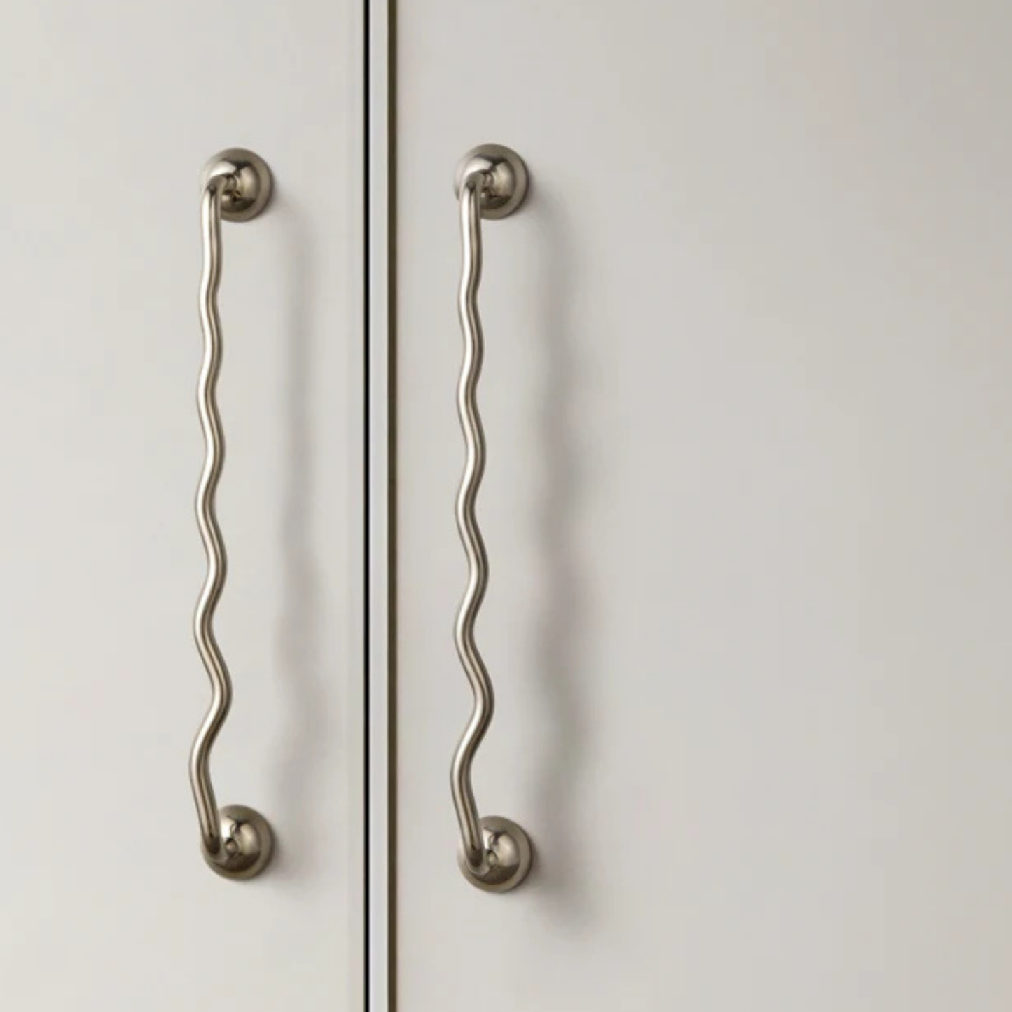 Wavy stainless steel cabinet handles installed on double doors